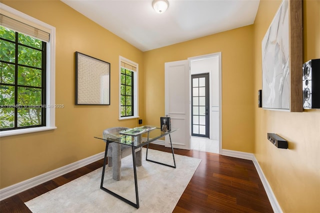 unfurnished office with baseboards, wood finished floors, and healthy amount of natural light