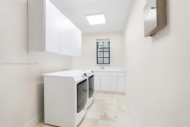 laundry area featuring separate washer and dryer, cabinet space, and baseboards