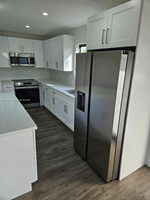 940 SW 78th Pl, Miami, FL 33144 - kitchen featuring appliances with stainless steel finishes, white cabinets, dark wood finished floors, light stone countertops, and decorative backsplash