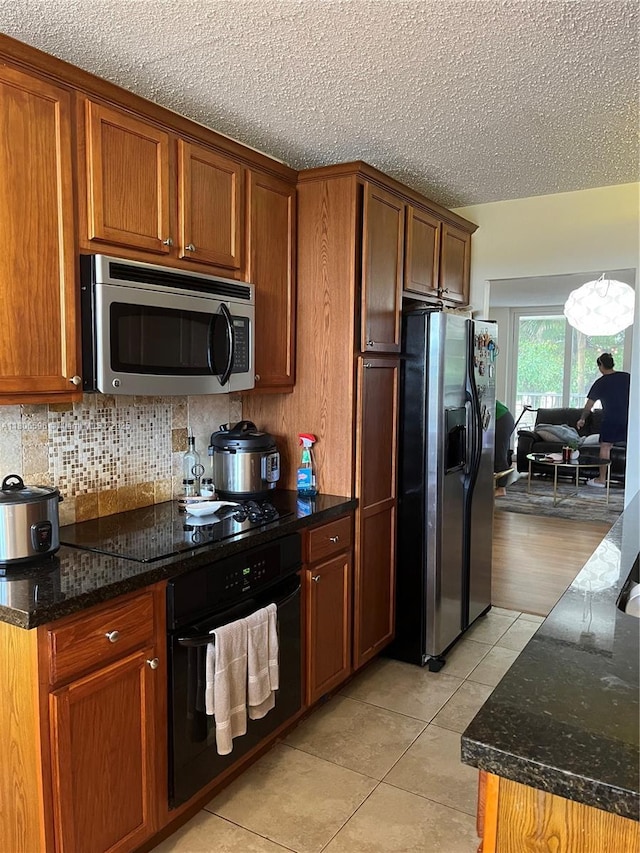 250 Jacaranda Dr Unit 303, Plantation, FL 33324 - kitchen featuring black appliances, light tile patterned flooring, dark stone countertops, tasteful backsplash, and a textured ceiling