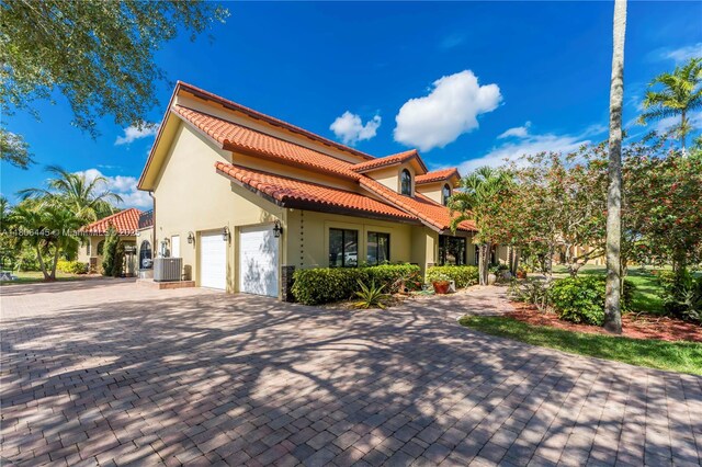 11915 Green Oak Dr, Davie, FL 33330 - view of side of home featuring stucco siding, a garage, central air condition unit, and a tile roof