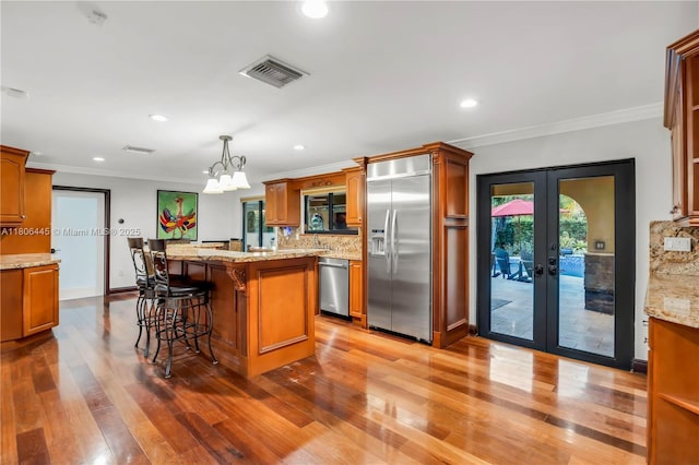 11915 Green Oak Dr, Davie, FL 33330 - kitchen with appliances with stainless steel finishes, french doors, a kitchen island, ornamental molding, and wood finished floors