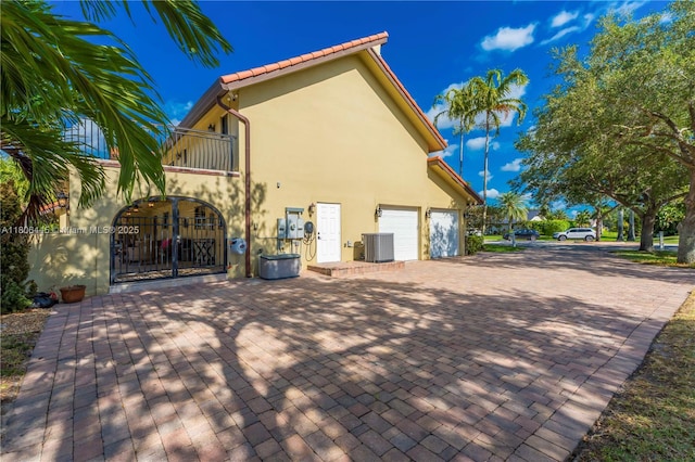 11915 Green Oak Dr, Davie, FL 33330 - view of side of home featuring a balcony, cooling unit, stucco siding, an attached garage, and driveway