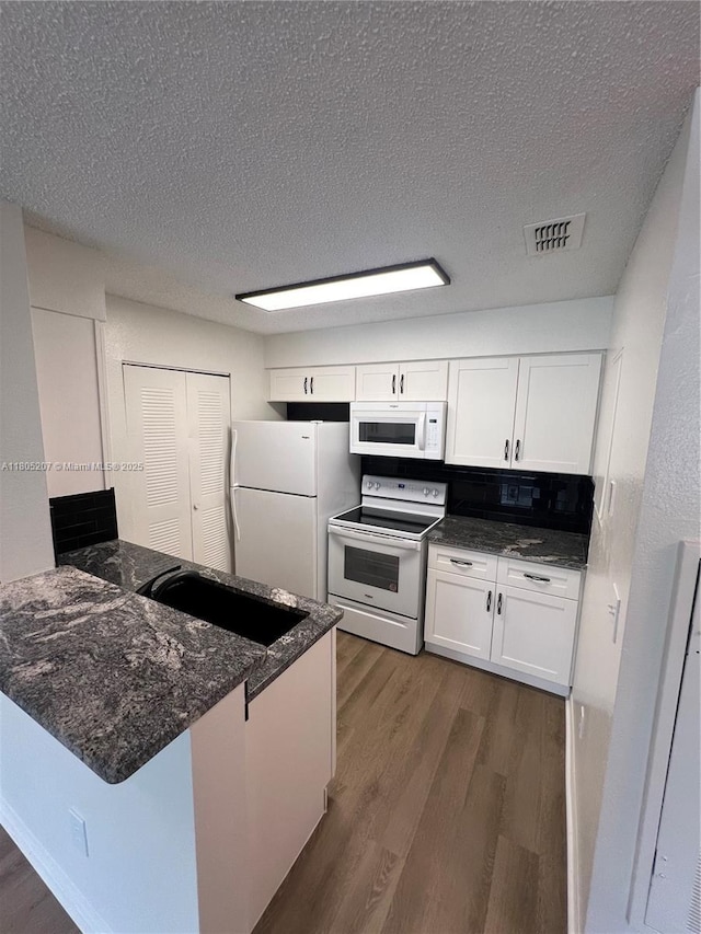 1055 S Hiawassee Rd Unit 2014, Orlando, FL 32835 - kitchen featuring white appliances, dark wood-style flooring, white cabinets, a peninsula, and a textured ceiling