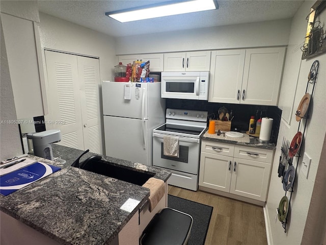 1055 S Hiawassee Rd Unit 2014, Orlando, FL 32835 - kitchen featuring white appliances, light wood-style floors, white cabinetry, dark stone counters, and a textured ceiling