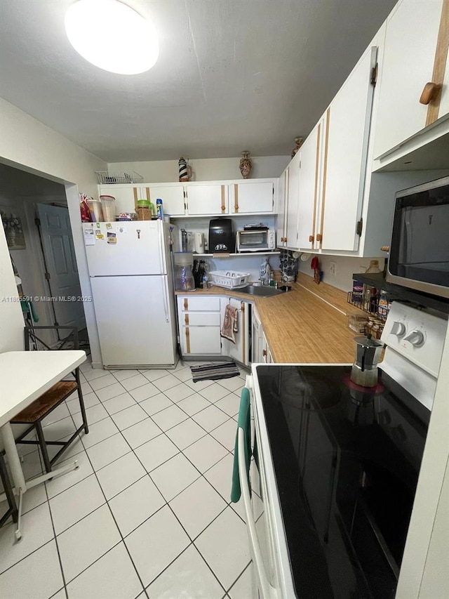 7400 NW 17th St Unit 209, Plantation, FL 33313 - kitchen with freestanding refrigerator, range with electric cooktop, stainless steel microwave, white cabinetry, and light countertops