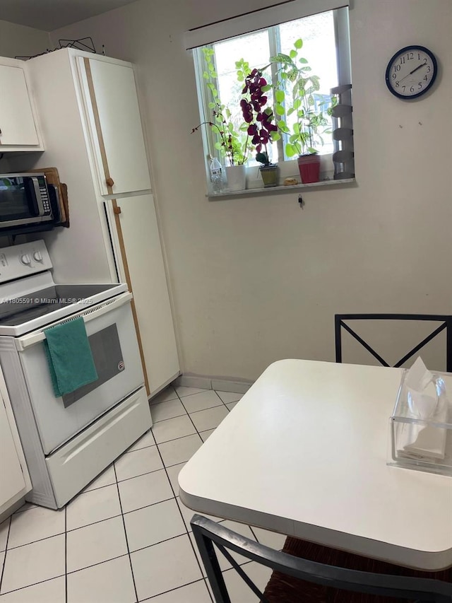 7400 NW 17th St Unit 209, Plantation, FL 33313 - kitchen featuring white electric range, stainless steel microwave, light tile patterned floors, white cabinetry, and light countertops