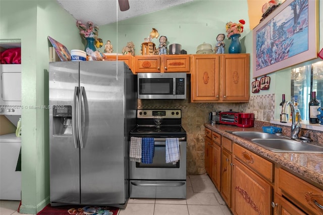 2401 NW 56th Ave Unit 3-202, Lauderhill, FL 33313 - kitchen featuring appliances with stainless steel finishes, a sink, stacked washer and clothes dryer, light tile patterned floors, and brown cabinetry