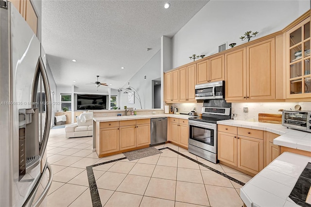 5362 NW 108th Way, Coral Springs, FL 33076 - kitchen featuring appliances with stainless steel finishes, tile counters, open floor plan, light brown cabinetry, and a peninsula