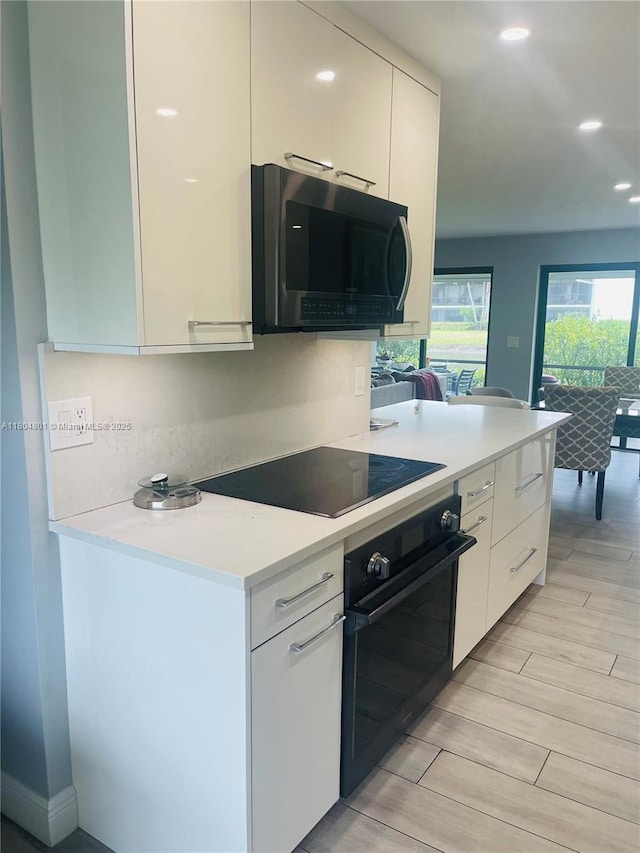 7736 Lakeside Blvd Unit G205, Boca Raton, FL 33434 - kitchen featuring black appliances, light countertops, white cabinetry, modern cabinets, and light wood-type flooring