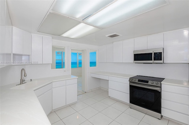 5255 Collins Ave Unit 14D, Miami Beach, FL 33140 - kitchen with appliances with stainless steel finishes, white cabinetry, light tile patterned floors, and light countertops