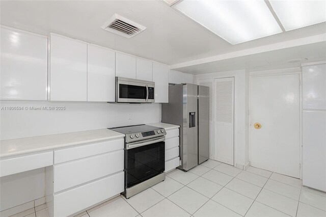 5255 Collins Ave Unit 14D, Miami Beach, FL 33140 - kitchen with stainless steel appliances, white cabinetry, light countertops, light tile patterned floors, and modern cabinets