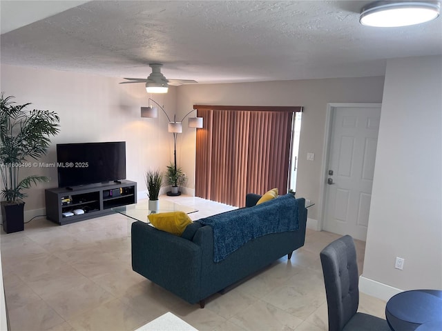 living area with ceiling fan, a textured ceiling, and baseboards