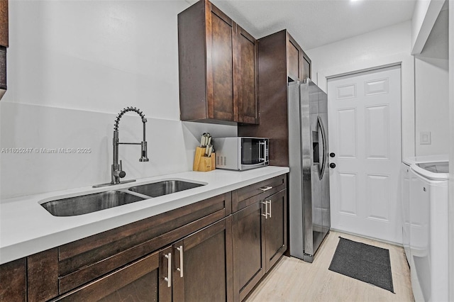 4029 SW 22nd St, West Park, FL 33023 - kitchen with appliances with stainless steel finishes, a sink, washer and dryer, dark brown cabinetry, and light countertops
