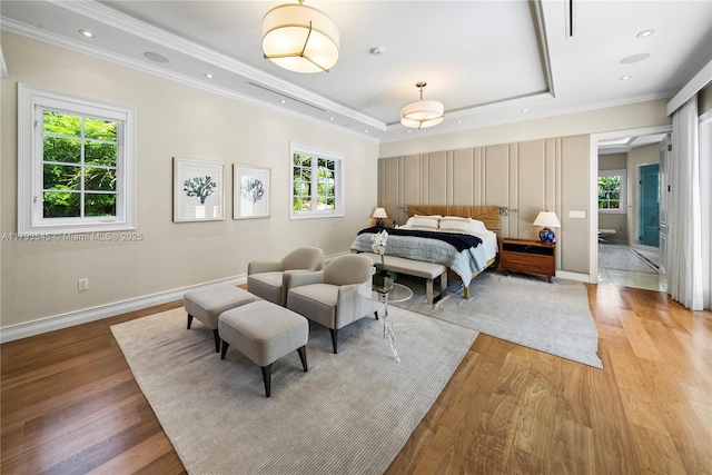 bedroom featuring light wood-type flooring, multiple windows, crown molding, and a raised ceiling