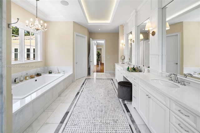 bathroom featuring a chandelier, a garden tub, vanity, inlaid floor details, and a raised ceiling