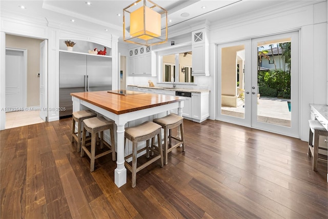 kitchen featuring butcher block counters, french doors, a kitchen breakfast bar, white cabinetry, and crown molding