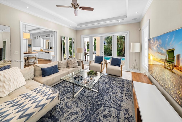 living area with ceiling fan, a tray ceiling, recessed lighting, and ornamental molding