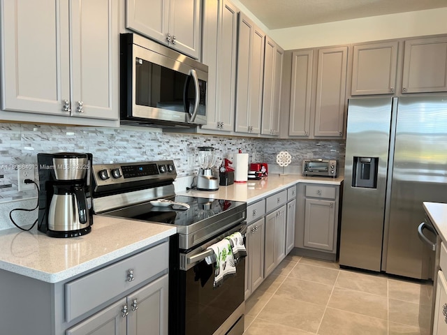 726 Longboat, Davenport, FL 33896 - kitchen with stainless steel appliances, gray cabinetry, light tile patterned floors, tasteful backsplash, and light stone countertops