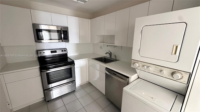 625 Biltmore Way Unit 707, Coral Gables, FL 33134 - kitchen with stainless steel appliances, stacked washing machine and dryer, a sink, light countertops, and light tile patterned floors