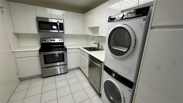 625 Biltmore Way Unit 707, Coral Gables, FL 33134 - kitchen featuring stacked washer and clothes dryer, stainless steel appliances, light countertops, light tile patterned flooring, and white cabinets