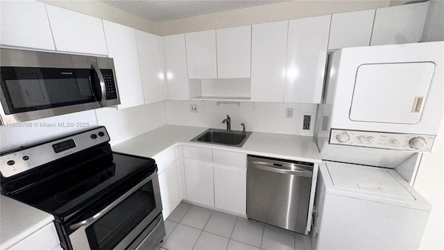 625 Biltmore Way Unit 707, Coral Gables, FL 33134 - kitchen with appliances with stainless steel finishes, stacked washing machine and dryer, a sink, white cabinetry, and light countertops