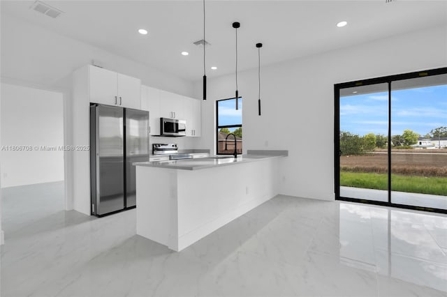 2518 26th St W, Lehigh Acres, FL 33971 - kitchen with appliances with stainless steel finishes, white cabinets, light marble finish floors, a peninsula, and decorative light fixtures