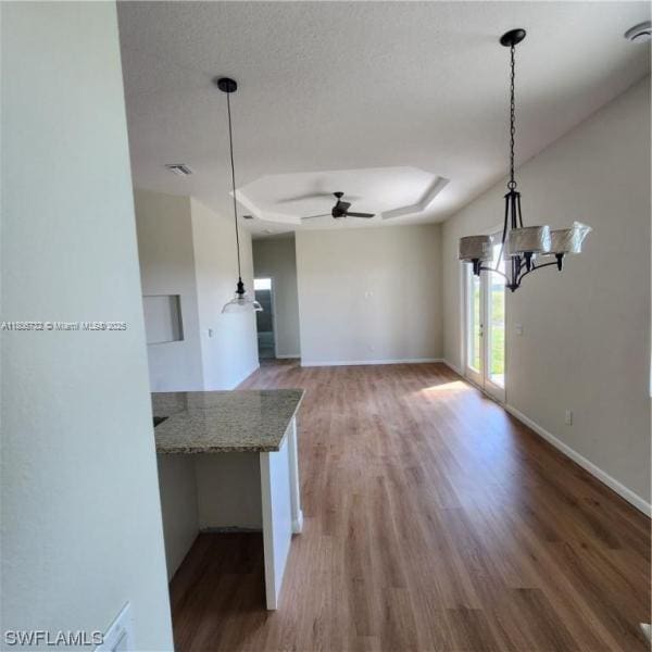 1818 Inwood Rd, La Belle, FL 33935 - unfurnished dining area with ceiling fan, light wood finished floors, a tray ceiling, and baseboards