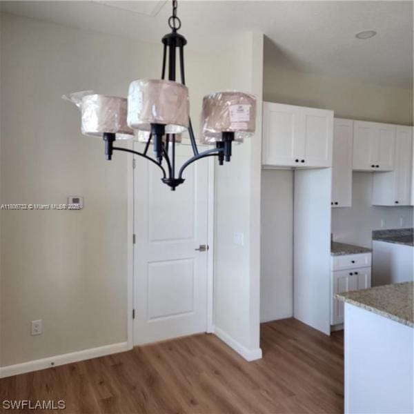 1818 Inwood Rd, La Belle, FL 33935 - kitchen with wood finished floors, white cabinets, a chandelier, and baseboards