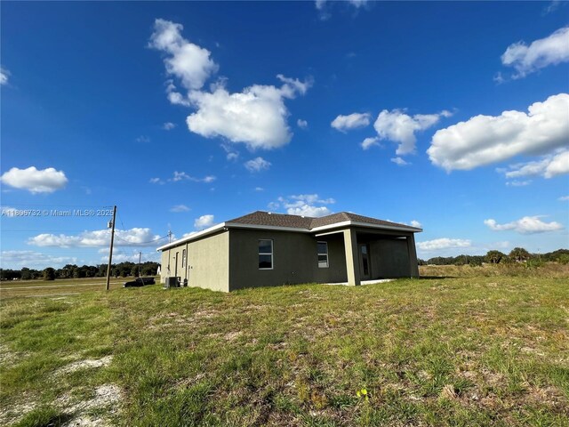 1818 Inwood Rd, La Belle, FL 33935 - rear view of property with stucco siding and a yard