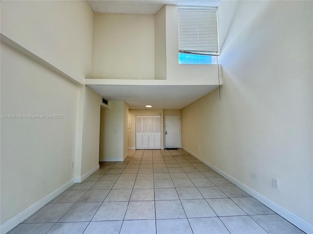 8810 Fontainebleau Blvd Unit 318, Miami, FL 33172 - unfurnished living room featuring a high ceiling, baseboards, and light tile patterned flooring