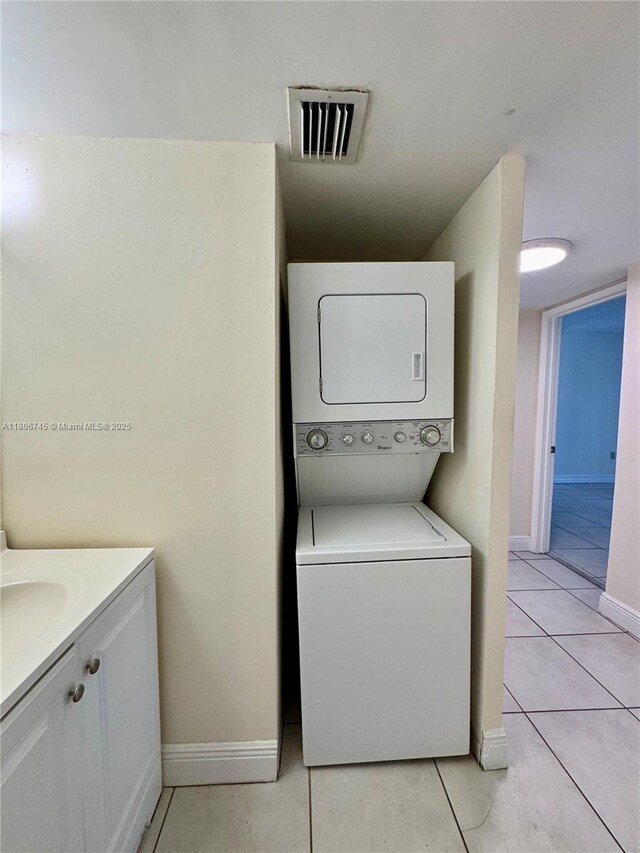 8810 Fontainebleau Blvd Unit 318, Miami, FL 33172 - washroom with stacked washer and clothes dryer, light tile patterned flooring, and baseboards