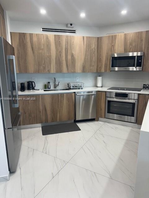 19500 Turnberry Way Unit 12A, Aventura, FL 33180 - kitchen featuring appliances with stainless steel finishes, modern cabinets, light marble finish flooring, and brown cabinets
