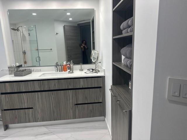 19500 Turnberry Way Unit 12A, Aventura, FL 33180 - bathroom featuring marble look tiles, double vanity, a shower stall, and recessed lighting