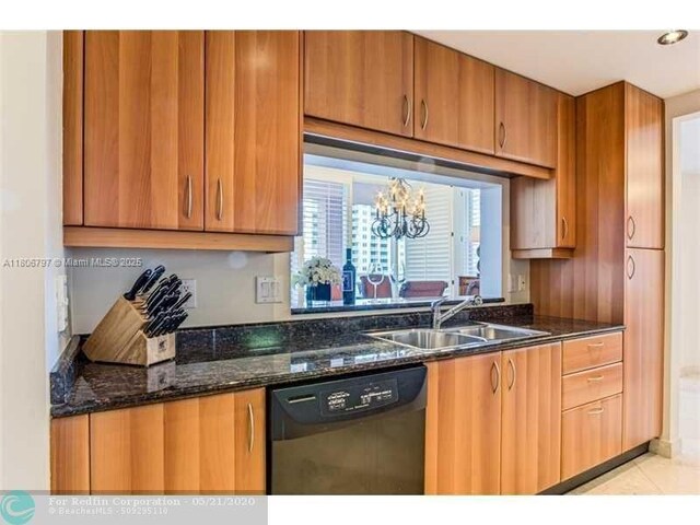 2100 N Ocean Blvd Unit 5B, Fort Lauderdale, FL 33305 - kitchen featuring black dishwasher, a sink, dark stone countertops, brown cabinets, and light tile patterned floors