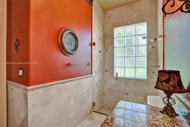 10233 NW 66th Dr, Parkland, FL 33076 - bathroom featuring a stall shower, plenty of natural light, tile walls, and wainscoting