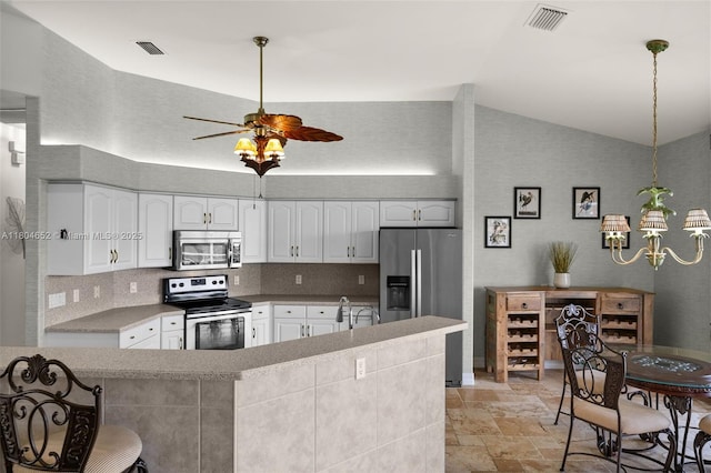 249 SW 37th Ln, Cape Coral, FL 33914 - kitchen featuring appliances with stainless steel finishes, stone tile floors, a chandelier, lofted ceiling, and white cabinetry