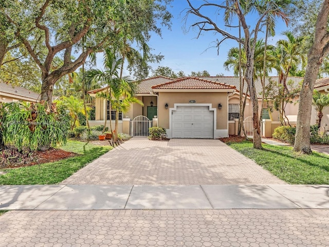 2530 E Aragon Blvd Unit 1, Sunrise, FL 33313 - mediterranean / spanish home with a gate, decorative driveway, stucco siding, a tiled roof, and an attached garage