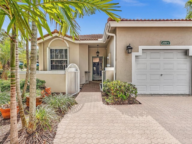 2530 E Aragon Blvd Unit 1, Sunrise, FL 33313 - view of exterior entry featuring a garage, stucco siding, a tiled roof, and decorative driveway