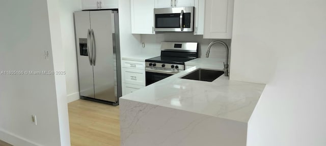 5570 NW 44th St Unit 209A, Lauderhill, FL 33319 - kitchen featuring appliances with stainless steel finishes, a sink, light stone countertops, white cabinets, and light wood-style floors