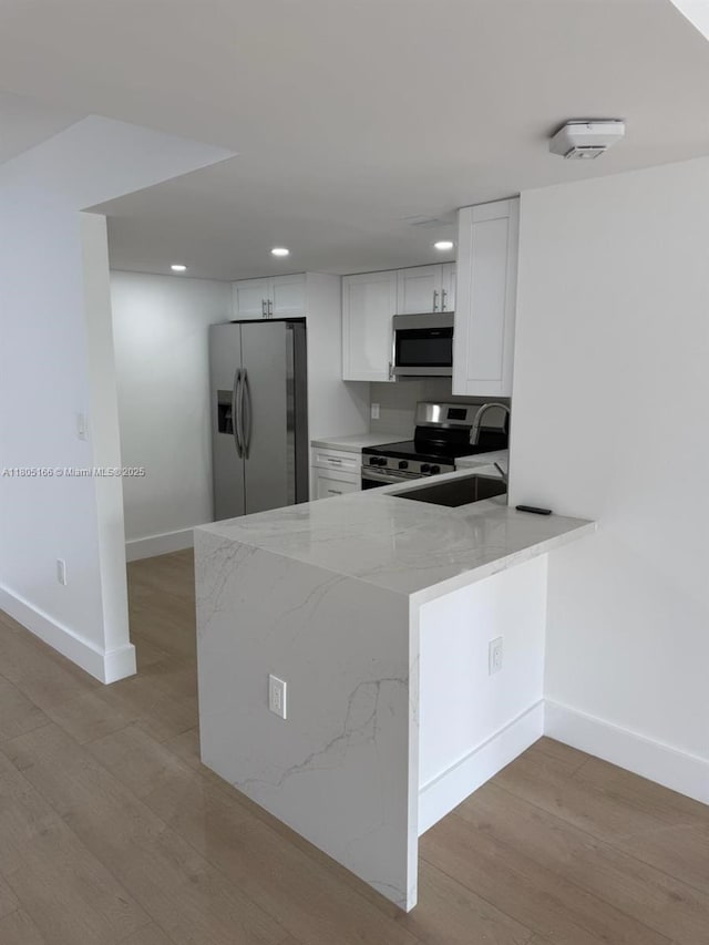 5570 NW 44th St Unit 209A, Lauderhill, FL 33319 - kitchen featuring stainless steel appliances, light stone countertops, recessed lighting, white cabinets, and light wood-style flooring