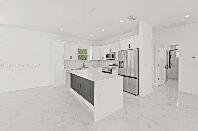 2506 5th St SW, Lehigh Acres, FL 33976 - kitchen featuring stainless steel appliances, a sink, a kitchen island, baseboards, and white cabinetry