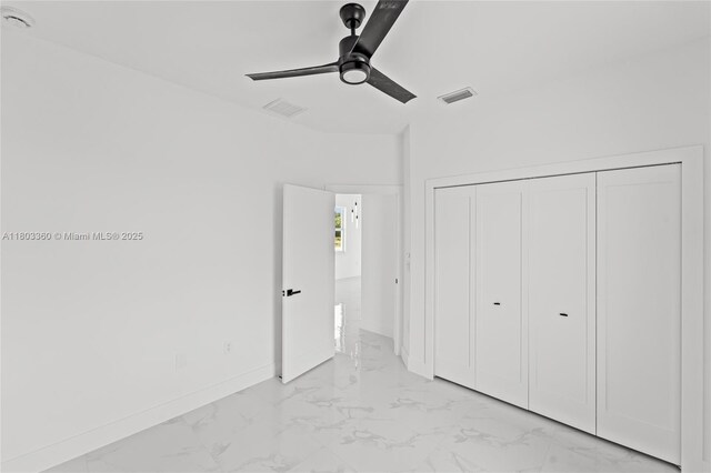 2506 5th St SW, Lehigh Acres, FL 33976 - unfurnished bedroom featuring light marble finish floors, a closet, baseboards, and ceiling fan