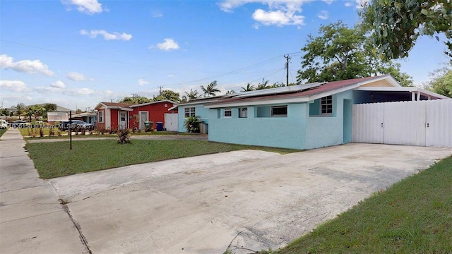 18502 NW 23rd Ct, Miami Gardens, FL 33056 - view of front facade featuring roof mounted solar panels, driveway, stucco siding, and a gate