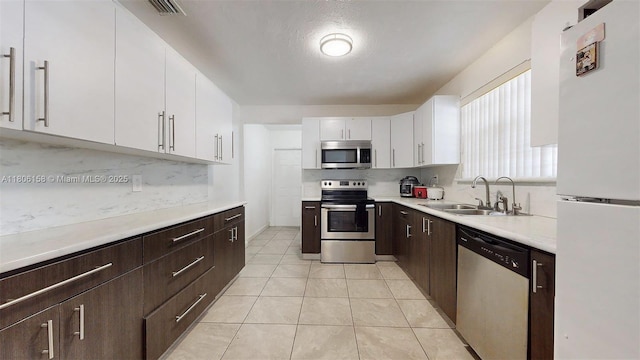 18502 NW 23rd Ct, Miami Gardens, FL 33056 - kitchen featuring stainless steel appliances, white cabinets, decorative backsplash, dark brown cabinets, and light countertops