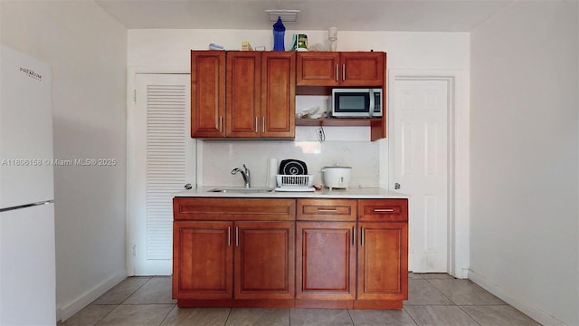 18502 NW 23rd Ct, Miami Gardens, FL 33056 - kitchen with freestanding refrigerator, stainless steel microwave, light countertops, light tile patterned floors, and tasteful backsplash