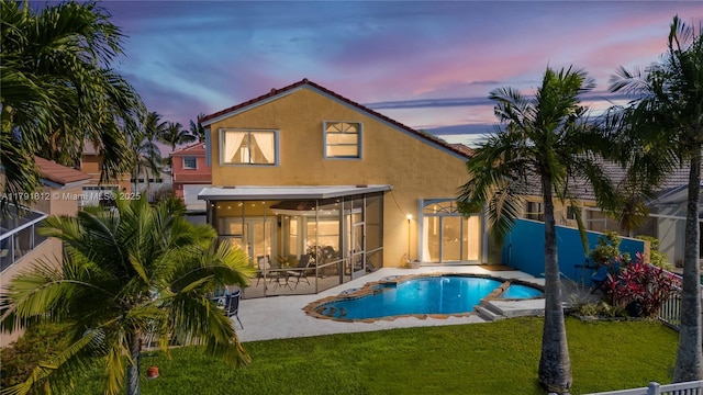 1060 NW 192nd Ave, Pembroke Pines, FL 33029 - back of house at dusk featuring stucco siding, a sunroom, and a patio