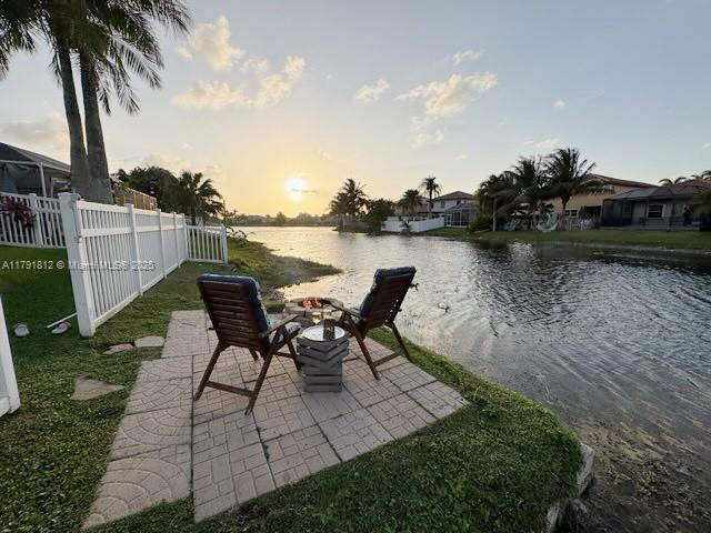 1060 NW 192nd Ave, Pembroke Pines, FL 33029 - patio terrace at dusk with an outdoor fire pit, a water view, and a patio