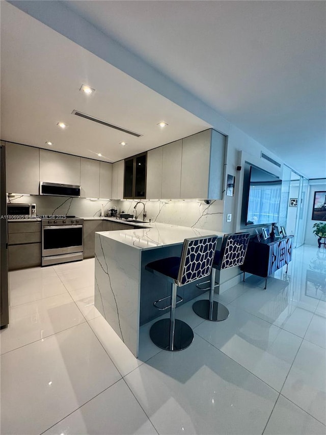 9801 Collins Ave Unit 19J, Bal Harbour, FL 33154 - kitchen with gas stove, a peninsula, tasteful backsplash, modern cabinets, and light stone countertops