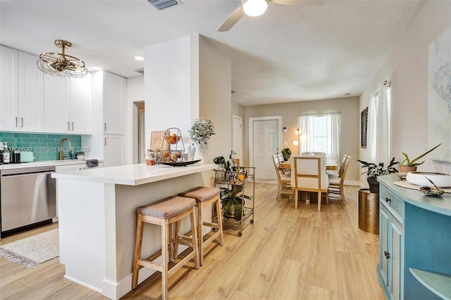 1222 S 14th Ct S, Lake Worth, FL 33460 - kitchen featuring stainless steel dishwasher, light wood-style floors, a kitchen breakfast bar, and light countertops